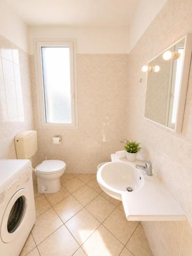a bathroom with a toilet sink and a washing machine at RESIDENCE STEFANIA - AGENZIA COCAL in Caorle
