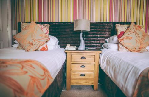 a bedroom with two beds and a lamp on a night stand at Royal Seven Stars Hotel in Totnes