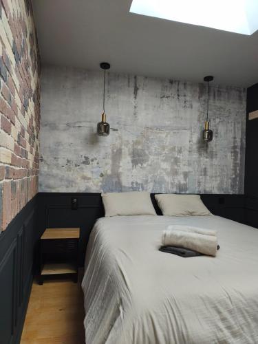 a bedroom with a bed and a brick wall at Escale à Clisson - l'Hippo Loft in Clisson