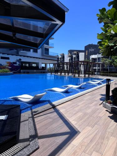 a swimming pool with lounge chairs on top of a building at K Avenue by Stay & Unwind Suites in Donggongon