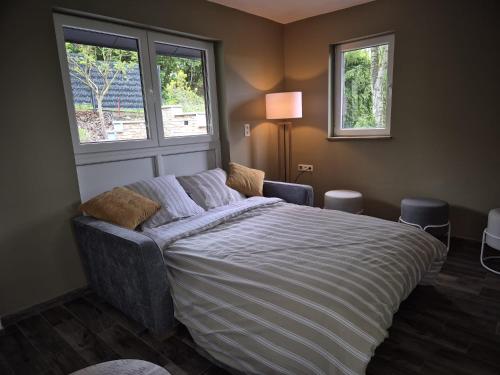 a bedroom with a bed and a couch and two windows at Villa bel horizon avec jacuzzi in Hotton