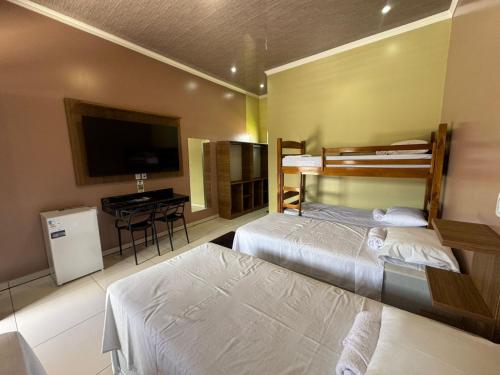a bedroom with two beds and a flat screen tv at Hotel Araújo in Capitão Poço