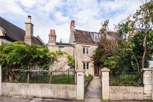an old house with a fence in front of it at Four bedroomed 18th century cosy cottage three miles from Bath City Centre in Batheaston