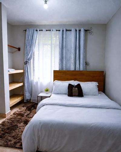 a bedroom with a large white bed with blue curtains at Rosewood Cozy homes in Mbeya