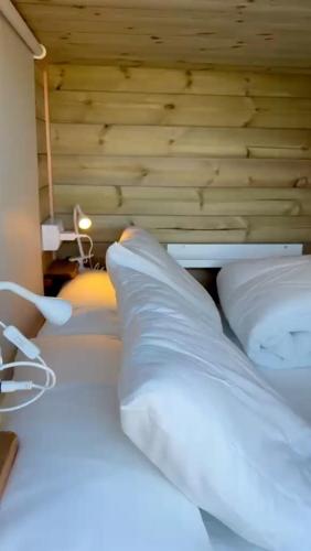 a bed with white pillows and a wooden wall at Nómada Hostel in El Palmar