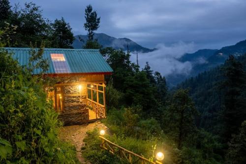 a cabin in the middle of a forest with lights at Gaunnie Valley - Jibhi in Jibhi