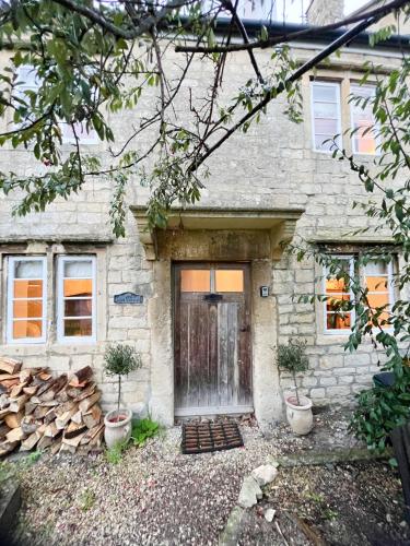 a stone house with a door and two potted plants at Four bedroomed 18th century cosy cottage three miles from Bath City Centre in Batheaston