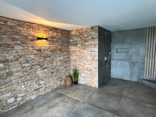 a bathroom with a brick wall and a shower at Villa bel horizon avec jacuzzi in Hotton