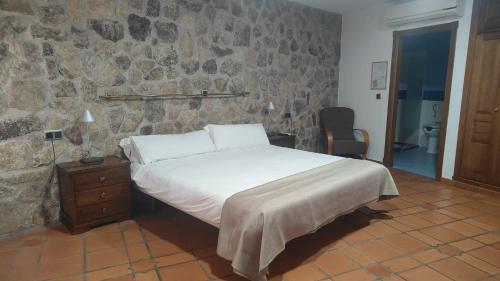 a bedroom with a bed and a stone wall at Ruralis Las Nogalas in Montánchez