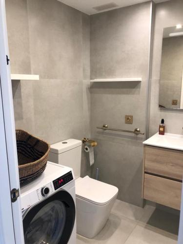 a bathroom with a washing machine next to a toilet at Al_andalus_404 in Alcossebre