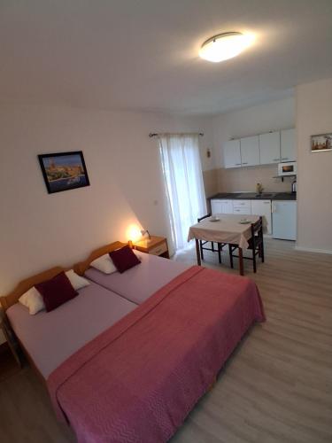 a bedroom with two beds and a table and a kitchen at Apartmani Kljunak in Zaton