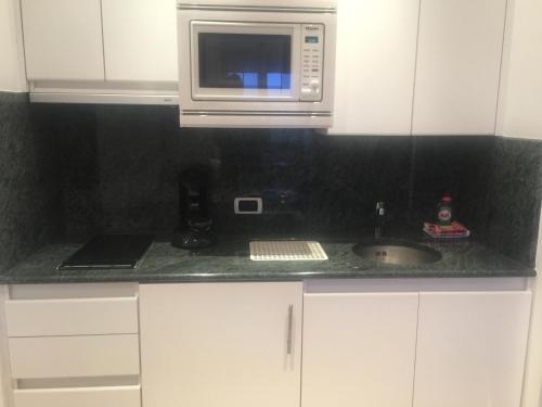 a kitchen with a sink and a microwave at PS Orion in Wenduine