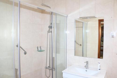 a bathroom with a shower and a sink and a mirror at Refúgio dos 3 Passos in Lanhas
