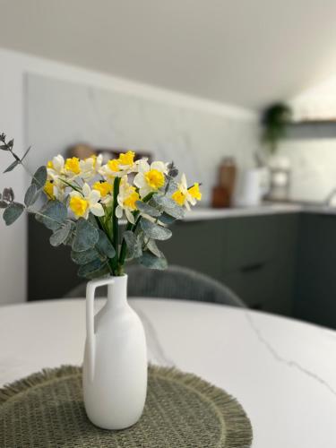 a white vase with yellow and white flowers on a table at Modern Design Apartment Salona I Stylish & Comfortable Solin I Split in Solin