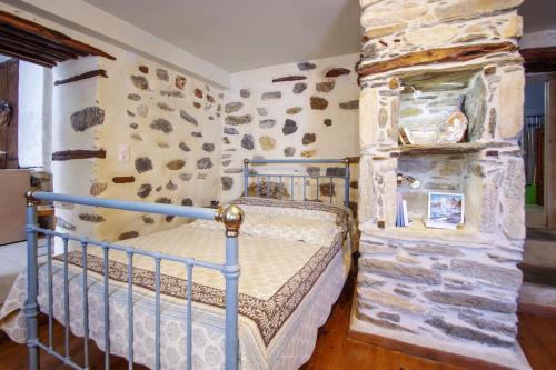 a bedroom with a bed and a stone wall at Next to the Bougainvillea! in Ano Syros