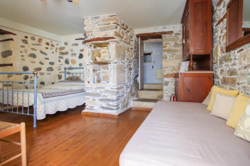 a room with a bed and a stone wall at Next to the Bougainvillea! in Ano Syros