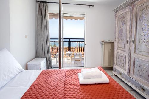ein Schlafzimmer mit einem Bett und einer großen Glasschiebetür in der Unterkunft Elgrecosuits in Limenaria