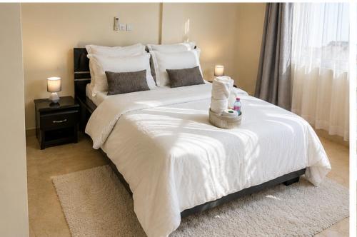 a bedroom with a white bed with two candles on it at Appartement cozy Bonamoussadi, WIFI & Goupe électrogène in Douala