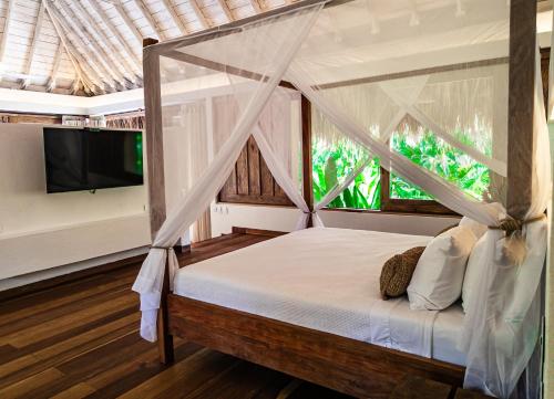 a bedroom with a canopy bed and a tv at Casa Bambu Tayrona, Los Naranjos in Los Naranjos