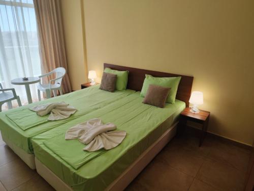 a bedroom with a green bed with two towels on it at Амон Ра 2 in Primorsko
