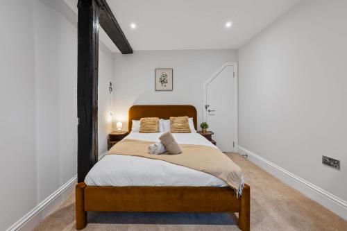 a bedroom with a large bed with a wooden headboard at Modern & Historic Mill Flat with Stream Views in Godalming