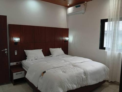 a bedroom with a large bed with a wooden headboard at T&J Harmony Lodge in Limbe
