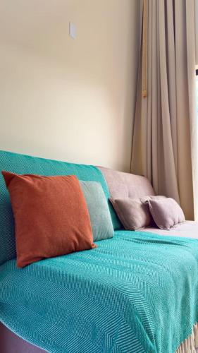 a bed with colorful pillows on top of it at Loft Duplex Moderno - 50m da Praia - Ar - Wi-Fi in Salinas da Margarida