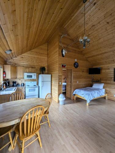 a kitchen and dining room with a table and a bed at NV Mountainview Chalets & RV Resort in McBride