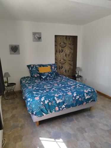 a bedroom with a bed with a blue comforter at La p'tite maison in Bordeaux-Saint-Clair