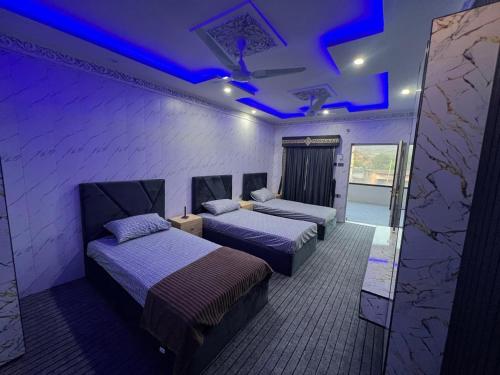 two beds in a room with purple lights at Ajk bed & Breakfast in Gura Gujarān