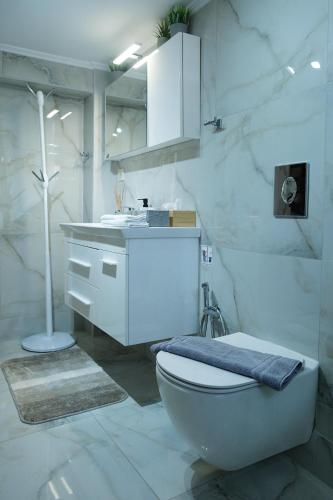 a white bathroom with a toilet and a sink at Evi's House in Kandia