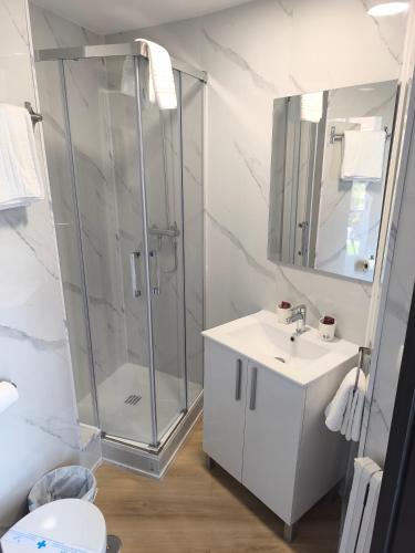 a white bathroom with a shower and a sink at Hostal Cafetería La Rotonda in Ourense