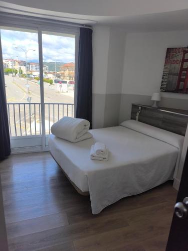 a bedroom with a bed and a large window at Hostal Cafetería La Rotonda in Ourense