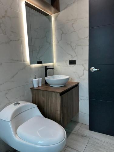 a bathroom with a white toilet and a sink at DLiam Home in Baños