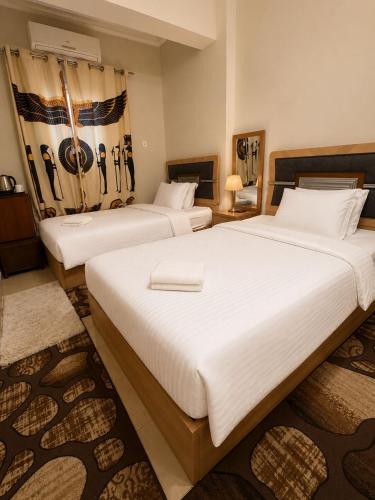 two beds in a hotel room with white sheets at Casa Latina pyramids view in Cairo
