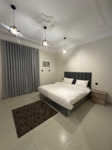 ein Schlafzimmer mit einem großen weißen Bett und Lichtern in der Unterkunft شقق نسائم ورد in Ta'if