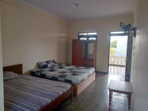 ein Schlafzimmer mit zwei Betten, einem Tisch und einem Fenster in der Unterkunft Hotel Brawijaya in Timuran