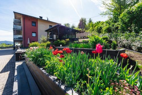 a garden with flowers and a building in the background at Boutique Apartments Daniela in Faak am See