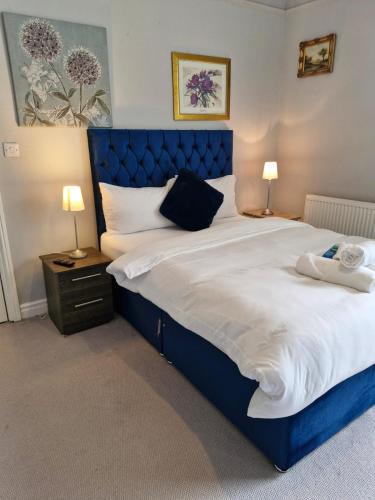 a large bed with a blue headboard in a bedroom at Grange House Budget Rooms in Leeds