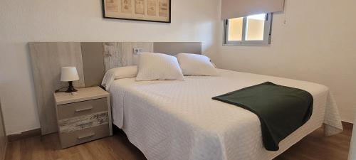 a bedroom with a bed with a green blanket on it at Calpe vistas al mar in Ifach