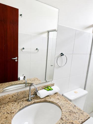 a bathroom with a sink and a toilet and a mirror at BURITI HOTEL Barra do Riacho Aracruz in Aracruz
