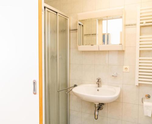 a white bathroom with a sink and a mirror at Zisterzienserstift Lilienfeld in Lilienfeld