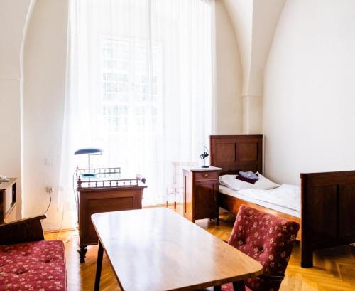a room with two beds and a table and chairs at Zisterzienserstift Lilienfeld in Lilienfeld