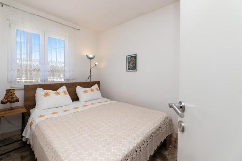 a white bedroom with a bed and a window at Kuća Lucija in Supetar