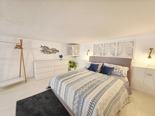 a white bedroom with a large bed with blue pillows at La Perla Blu in Calasetta