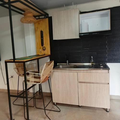 a kitchen with a sink and a counter with chairs at Suite campestre a 5 minutos del parque con aire acondicionado in Acacías