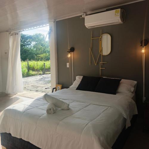 a bedroom with a large white bed with a window at Suite campestre a 5 minutos del parque con aire acondicionado in Acacías