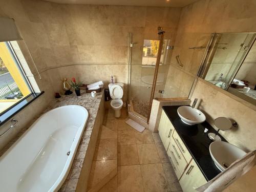 a bathroom with a tub and a sink and a toilet at Golden Feathers Lodge in Cape Town