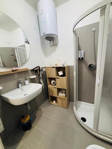 a bathroom with a sink and a shower with a mirror at Costa Silvia Villaggio Frisaia Vue imprenable sur la mer avec piscine in Trinità d'Agultu e Vignola