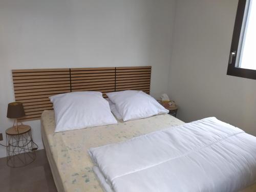 a bed with white sheets and pillows in a bedroom at Au coin des Lilas - studio 2 in Le Mans